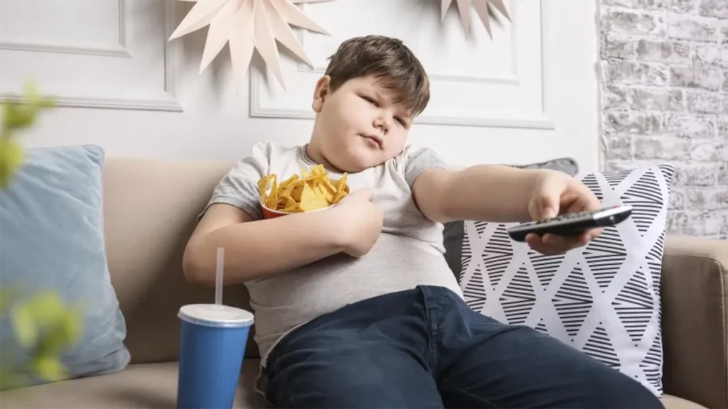 Fat boy watching TV and eating potato chips