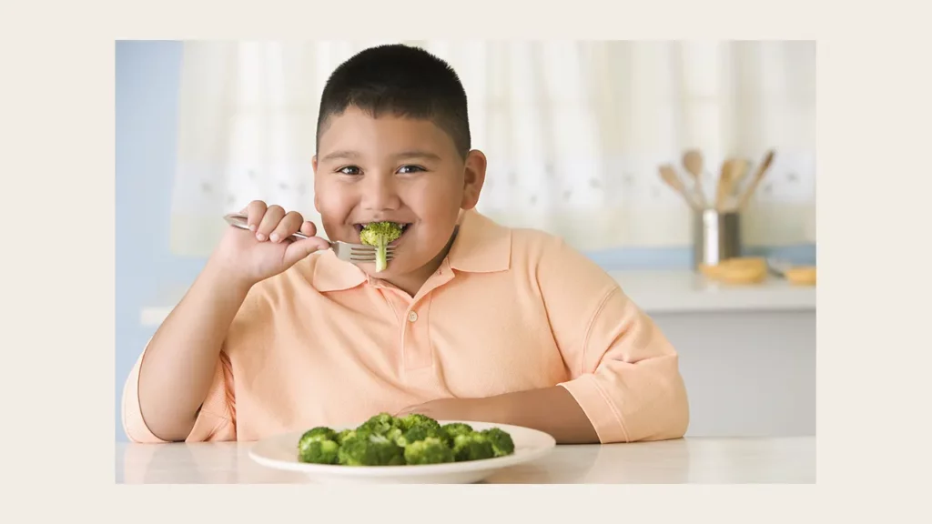 A boy eating broccoli