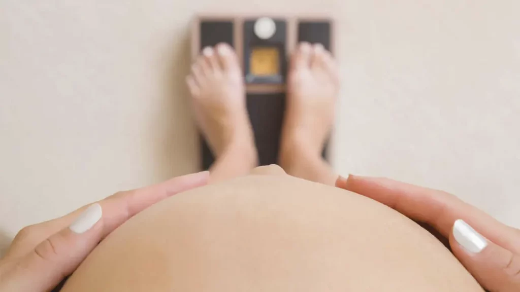 Pregnant woman weighing herself on a digital scale