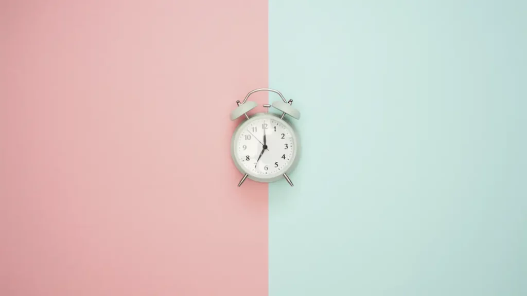 Schematic image of a clock on a table, half of which is pink and the other half is blue.