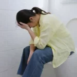 A woman sitting on the toilet for a long time due to constipation.
