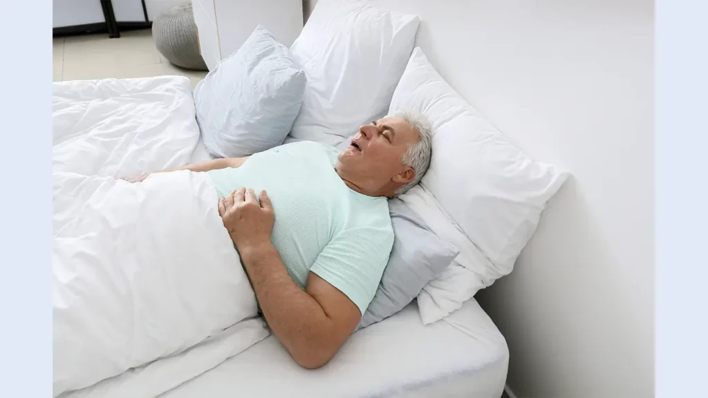 A man lying in bed breathing through his mouth.